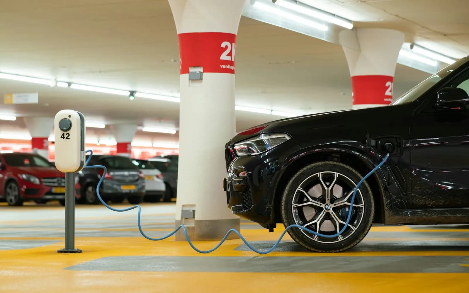 Véhicule électrique en charge sur une borne dans un parking souterrain de copropriété